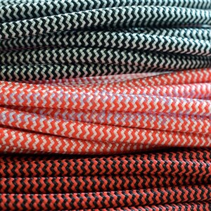 May include: Close-up of three spools of black and white, red and white, and red and black braided cord. The cord has a zig-zag pattern.