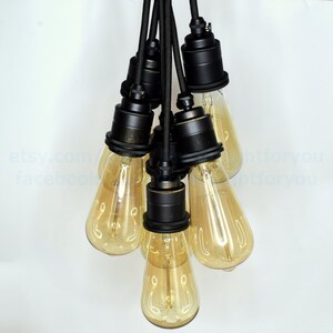 May include: A cluster of six black pendant light fixtures with clear glass bulbs hanging from black cords.