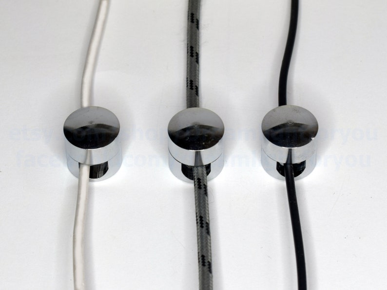 May include: Three chrome cable clips with different colored cords running through them. The cords are white, gray with black stripes, and black.