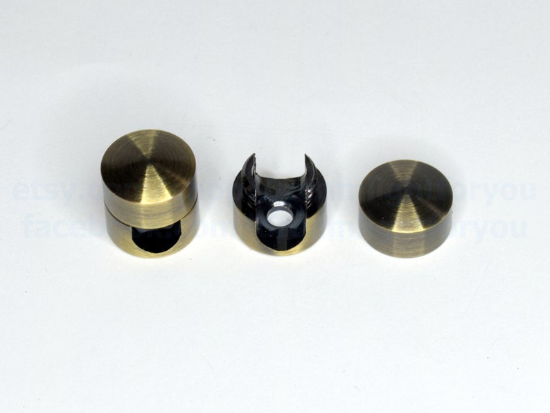 May include: Three antique gold metal curtain rod finials. The finials are round with a smooth, shiny surface. One finial is open on one side to allow for the insertion of a curtain rod.