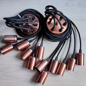 May include: A set of 10 copper pendant light fixtures with black electrical cords. The cords are twisted together and the fixtures are hanging from the ceiling.