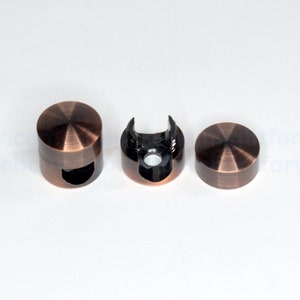 May include: Three copper-colored metal cable clips. One clip is open, showing the black plastic interior. The clips are round and have a smooth, polished finish.