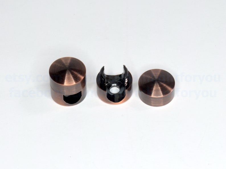 May include: Three copper-colored metal cable clips. One clip is open, showing the black plastic interior. The clips are round and have a smooth, polished finish.