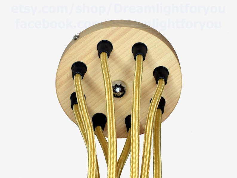May include: A round wooden ceiling canopy with six holes for electrical cords. The cords are gold and have black end caps.