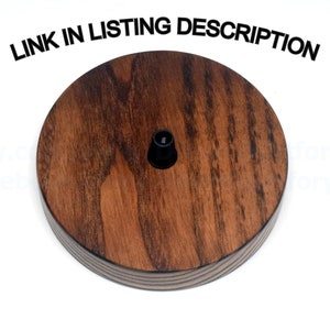 May include: A round wooden ceiling fixture with a dark brown stain. The fixture has a black electrical outlet in the center.