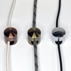 May include: Three cord end caps in different finishes: antique copper, antique brass, and chrome. Each cap has a round shape with a small hole for the cord to pass through.