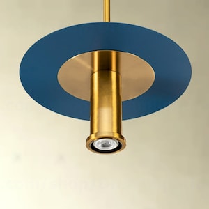 May include: A gold pendant light fixture with a blue circular shade. The light fixture has a cylindrical design and a white light bulb.