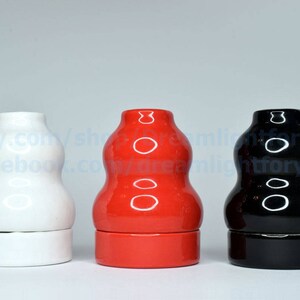 May include: Three ceramic bottle stoppers in different colors: white, red, and black. Each stopper has a rounded, bulbous shape with a smooth, glossy finish.