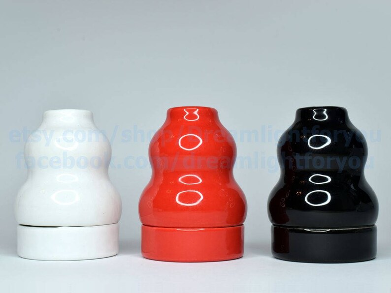 May include: Three ceramic bottle stoppers in different colors: white, red, and black. Each stopper has a rounded, bulbous shape with a smooth, glossy finish.