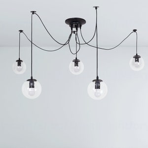May include: A black ceiling light fixture with five clear glass globe shades hanging from black cords.