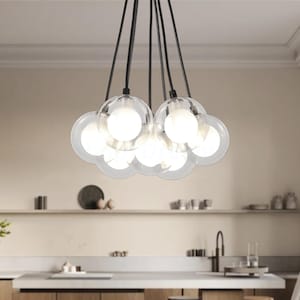 May include: Modern chandelier featuring multiple clear glass globes with bright interior lights. The fixture hangs from black cords, creating a cluster of illuminated spheres. The design is suitable for a kitchen or dining area.