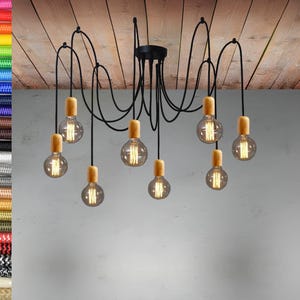 Puede incluir: Una lámpara de techo de metal negro con ocho bombillas colgantes. Las bombillas tienen un globo de vidrio transparente y una base de madera.