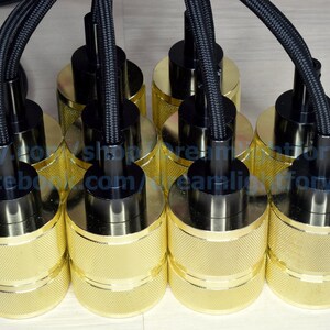 Puede incluir: Seis portal&aacute;mparas de metal de color dorado con cables trenzados negros. Los portal&aacute;mparas tienen un dise&ntilde;o texturizado y est&aacute;n conectados a los cables con tapas de pl&aacute;stico negro.