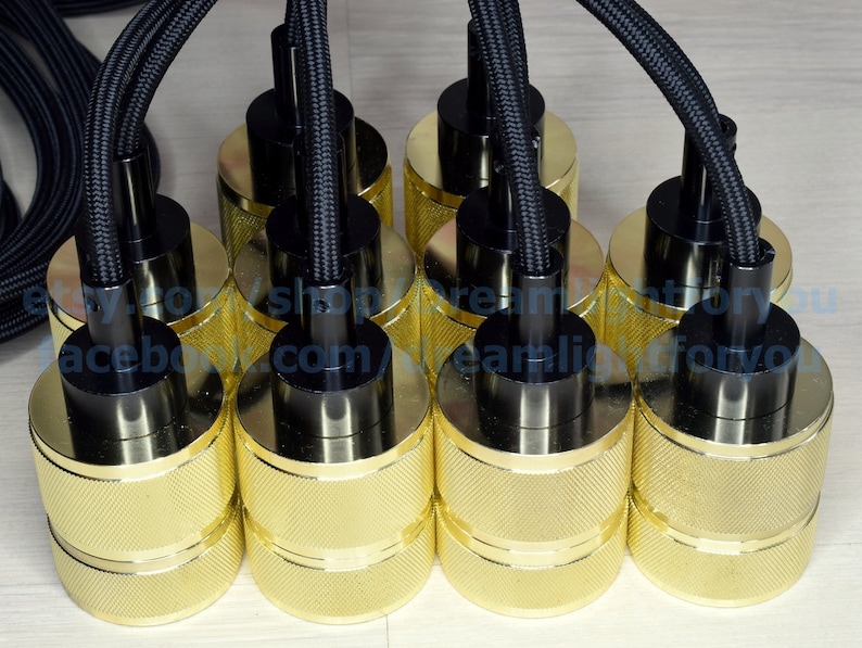 Puede incluir: Seis portal&aacute;mparas de metal de color dorado con cables trenzados negros. Los portal&aacute;mparas tienen un dise&ntilde;o texturizado y est&aacute;n conectados a los cables con tapas de pl&aacute;stico negro.