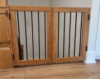 May include: A wooden gate with black metal bars, designed to block access to a staircase. The gate is made of light brown wood and has a simple, modern design.