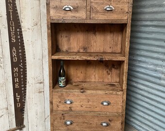 May include: A tall wooden cabinet with a shelf and multiple drawers. The cabinet has a rustic, distressed look and features metal drawer pulls. The cabinet is made of reclaimed wood and has a natural wood finish.