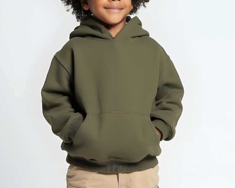 May include: An olive green hooded sweatshirt with a kangaroo pocket. The sweatshirt is made of a soft material and has ribbed cuffs and hem. The child is wearing khaki pants.