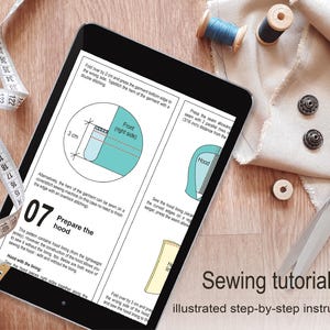 a sewing tutorial on a tablet, with various sewing tools such as scissors, thread, and fabric visible on a wooden surface.