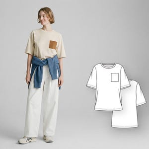 May include: A beige short-sleeved t-shirt with a brown pocket. The model is wearing white trousers and a blue sweater tied around the waist. A line drawing of the t-shirt is also shown.