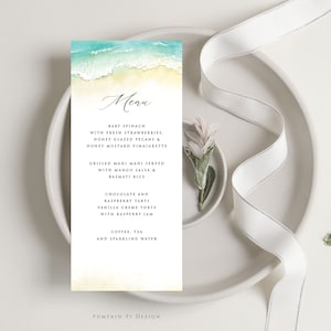 May include: A watercolor menu card with a beach scene featuring blue waves and yellow sand. The menu includes baby spinach with fresh strawberries, honey glazed pecans, honey mustard vinaigrette, grilled mahi mahi served with mango salsa and basmati rice, chocolate and raspberry tarts, vanilla creme torte with raspberry jam, coffee, tea, and sparkling water. The card is titled "Menu" and has the text "Pumpkin Pi Design" at the bottom.
