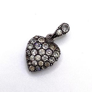 Peut inclure: Pendentif en forme de cœur argenté, orné de nombreux cristaux clairs et étincelants. Le pendentif comporte une petite boucle pour une chaîne et un cristal unique en haut. La forme de cœur est remplie de cristaux.