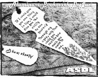 May include: A black and white image of two aluminium bookmarks. The larger bookmark is shaped like a spearhead and has the text "If I could give you one thing in life, I would give you the ability to see yourself through my eyes, only then would you realise how much you mean to me." The smaller bookmark is shaped like a teardrop and has the text "Always in my". Both bookmarks have a decorative design of leaves and flowers.