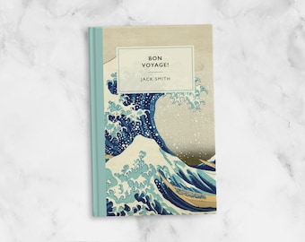 Op de afbeelding: Een boek met een blauw en wit golfontwerp op de omslag. De titel is "Bon Voyage!" en de auteur is "Jack Smith".
