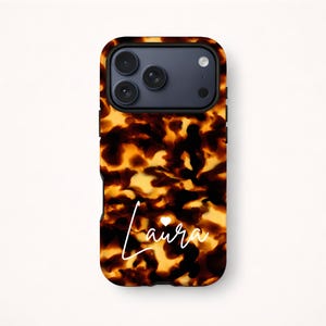 Puede incluir: Funda de teléfono con un diseño de carey en tonos marrones y amarillos. La funda tiene un borde negro y presenta el nombre "Laura" en escritura blanca con un pequeño símbolo de corazón.