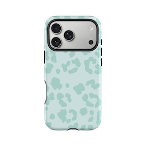 Può includere: Una custodia per telefono azzurra con un motivo leopardato. La custodia ha un bordo nero e un ritaglio per la fotocamera. Le macchie di leopardo sono di una tonalità di blu più chiara. La custodia è progettata per proteggere il telefono.