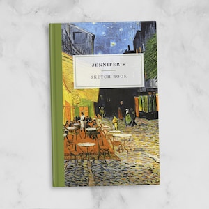 May include: A green and yellow sketchbook featuring a painting of a cafe at night. The title on the cover reads "Jennifer's Sketch Book".