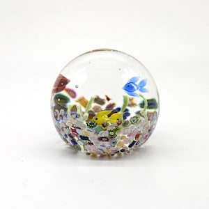 May include: A clear glass paperweight with a miniature underwater scene. The paperweight features a yellow and blue fish, green plants, and colorful decorative elements. The glass sphere is approximately 7.6 cm in diameter.