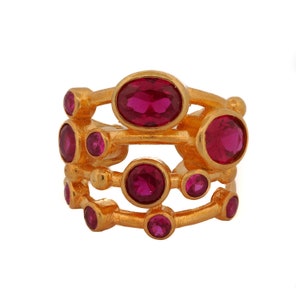 May include: Gold ring with multiple bands and pink gemstones. The ring has a cluster of round and oval-shaped stones.