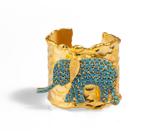 May include: Gold ring with a textured band and a turquoise elephant design.