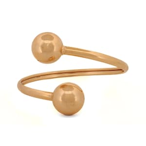 Op de afbeelding: Een gouden armband met twee ronde ballen aan de uiteinden.
