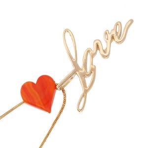 Collar de cadena dorada con carta de amor y corazón al atardecer