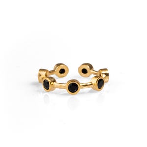 May include: Gold ring with six black round stones set in a row.