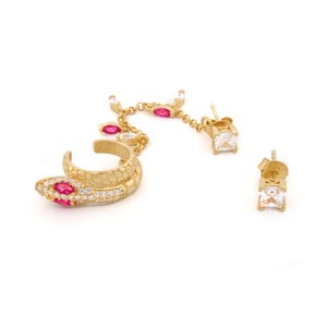 May include: Gold snake ear cuff with pink and white cubic zirconia stones. The cuff is connected to a chain with a dangling square cubic zirconia stone earring.
