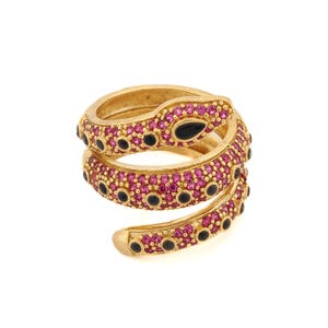 May include: A gold-toned ring with a coiled snake design. The snake is encrusted with pink and black gemstones.