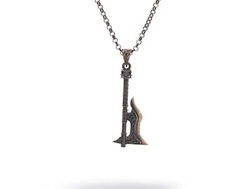 May include: A silver-colored pendant necklace featuring a detailed axe pendant. The axe has a textured handle and a curved blade. The chain is a simple, linked design. The necklace is displayed against a white background.