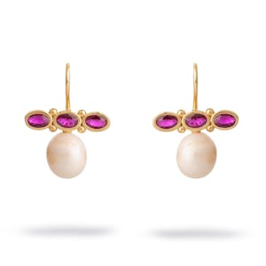 May include: A pair of gold-colored earrings with a drop design. Each earring features three oval-shaped, magenta-colored gemstones and a large, off-white, pear-shaped pearl. The earrings have a hook closure.