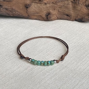 May include: A brown cord bracelet with turquoise and silver beads.