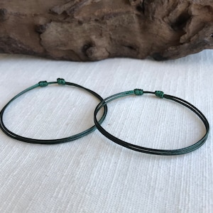 May include: Two green string bracelets with knots on each side.