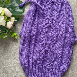 May include: Purple knitted sweater with a cable knit pattern and a drawstring at the neck. The sweater has a textured look and is made with a soft yarn. The text "@Lelina_mama" is visible at the bottom of the sweater.