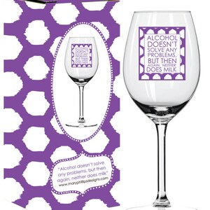 Puede incluir: Una copa de vino de vidrio transparente con un diseño morado y el texto "El alcohol no resuelve ningún problema, pero luego, la leche tampoco." La copa está en una caja con un patrón de lunares morados y blancos.