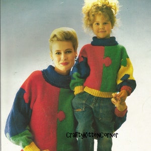 Puede incluir: Un suéter de punto rojo, verde, azul y amarillo con un diseño de pieza de rompecabezas. El suéter lo lleva puesto una mujer y un niño. El texto "CraftyKittenCorner" es visible en la imagen.