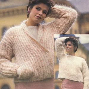 Könnte beinhalten: Ein weißer Strickcardigan mit Schalkragen und zwei Knöpfen. Der Cardigan hat eine flauschige Textur und wird von einer Person mit kurzen braunen Haaren getragen.