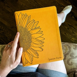 May include: A yellow leather-bound journal with a gold sunflower design and the name "Jessica Anne" embossed on the front cover.