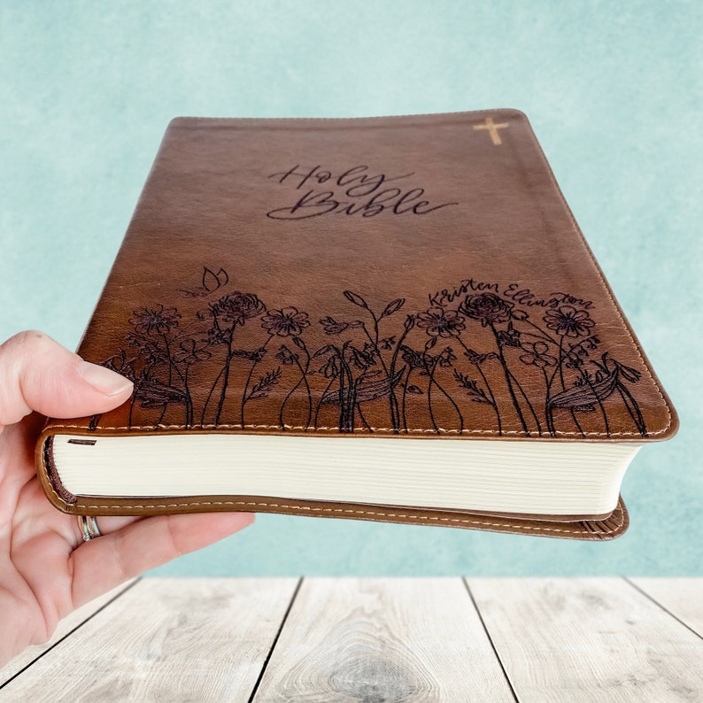 A New International Version Journaling by Zondervan Publishing in Tan. It has a design of Grass and Flowers engraved on it. It is hand lettered with calligraphy and makes a beautiful Christian gift, Gods Word, Scripture, 9780310455271