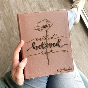 May include: A pink journal with the words "called beloved kept" and a floral design. The journal cover has a textured appearance and the text is in a cursive font. The name "E. O. Hendon" is printed at the bottom.