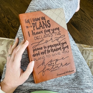 Op de afbeelding: Een bruin lederen dagboek met een beige omslag en een citaat uit Jeremia 29:11, "Want ik weet welke plannen ik voor jullie heb, spreekt de Heer, plannen van welzijn en niet van onheil, om jullie een toekomst en hoop te geven." Het citaat is geschreven in een decoratief handschrift.